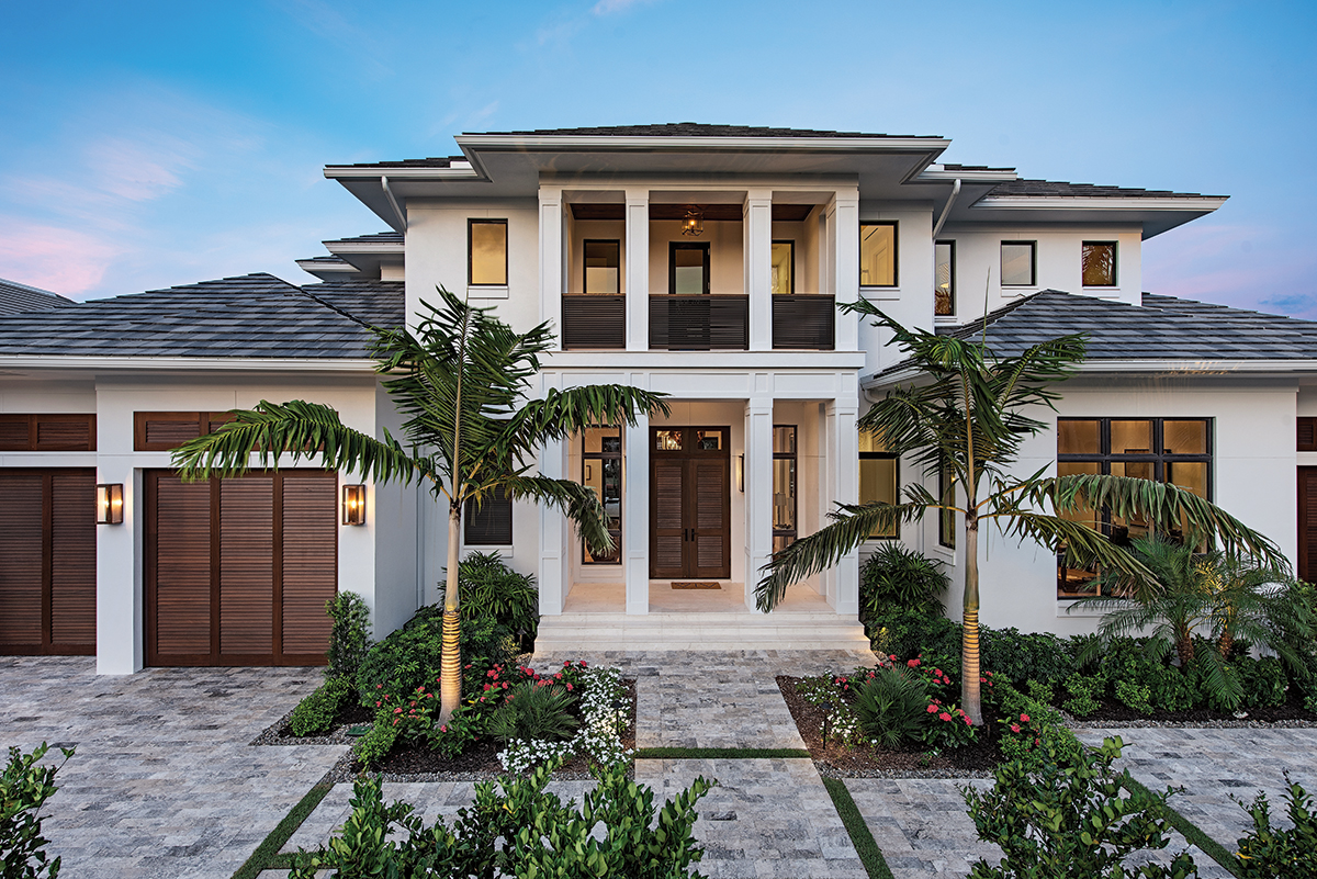 The exterior of the home is grand with large columns and a path of varietal silver and gray travertine pavers that speak to the gray Stone Mountain Blend roofing. Bands of lush green grass intercept stone pavers to create dramatic curb appeal while bountiful native foliage skirt the premises.